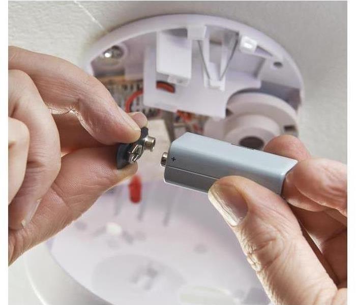 Battery being checked in a smoke detector.